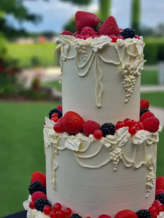 Détail d’un Lambeth cake mariage avec fraises framboises mûres groseilles et grappes de vigne pochées en crème ivoire